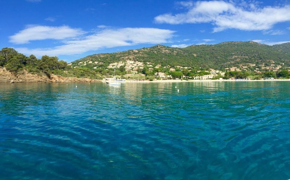 Plage avec des eaux cristallines avec un arrière plan montagneux.